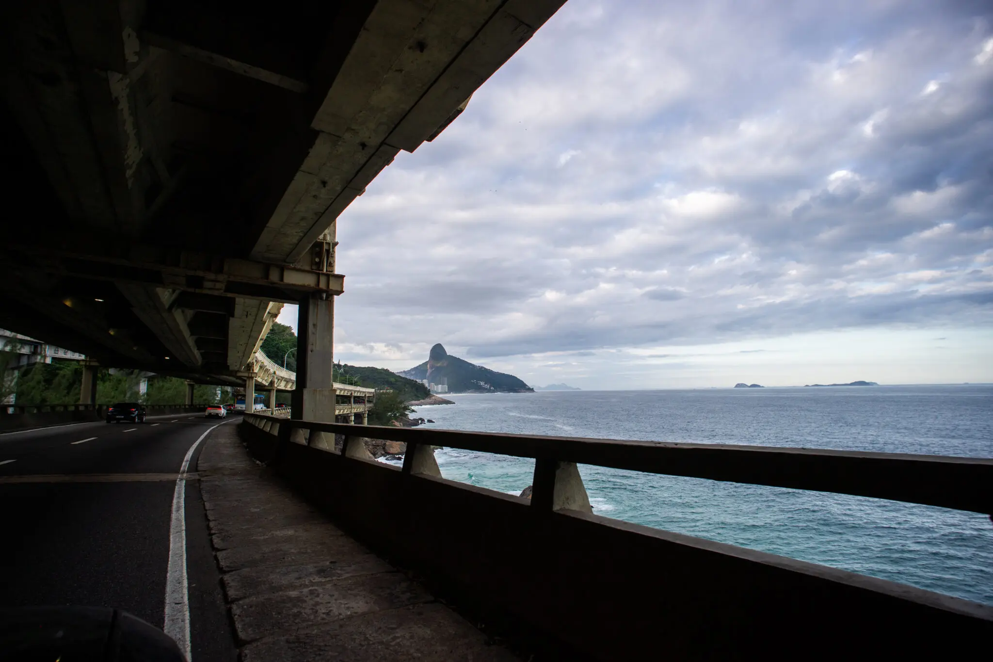 Estrada ao lado do mar com ponte e muro de proteção.