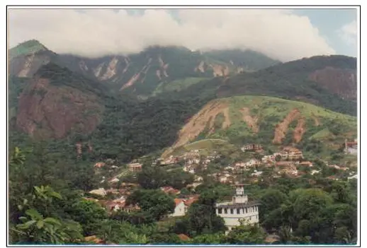 Cidade montanhosa com casas coloridas e vegetação verde.