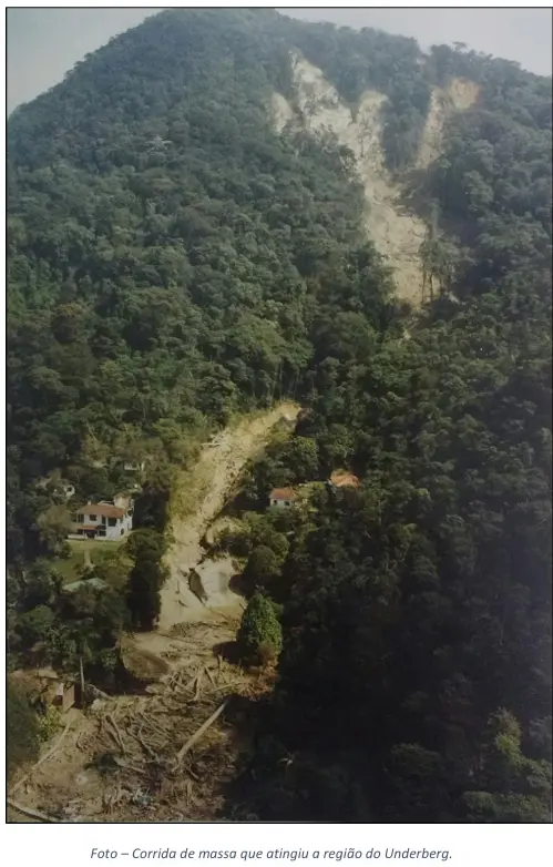 Área montanhosa com vegetação densa, casa branca e caminho de terra.