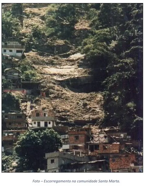 Comunidade residencial em encosta com casas de tijolos vermelhos e vegetação verde.