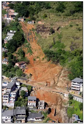 Deslizamento de terra com casa destruída e vegetação verde.