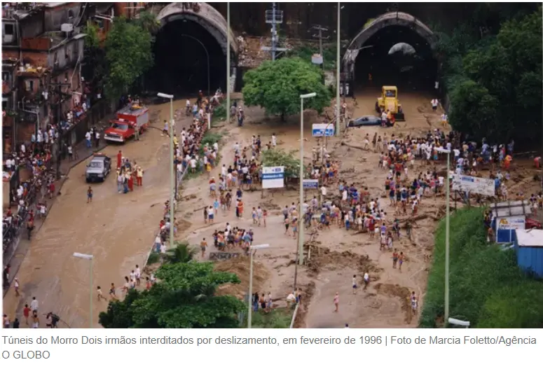Desastre natural em 1996, com pessoas caminhando em ruas inundadas e multidão perto de túneis cobertos de lama.