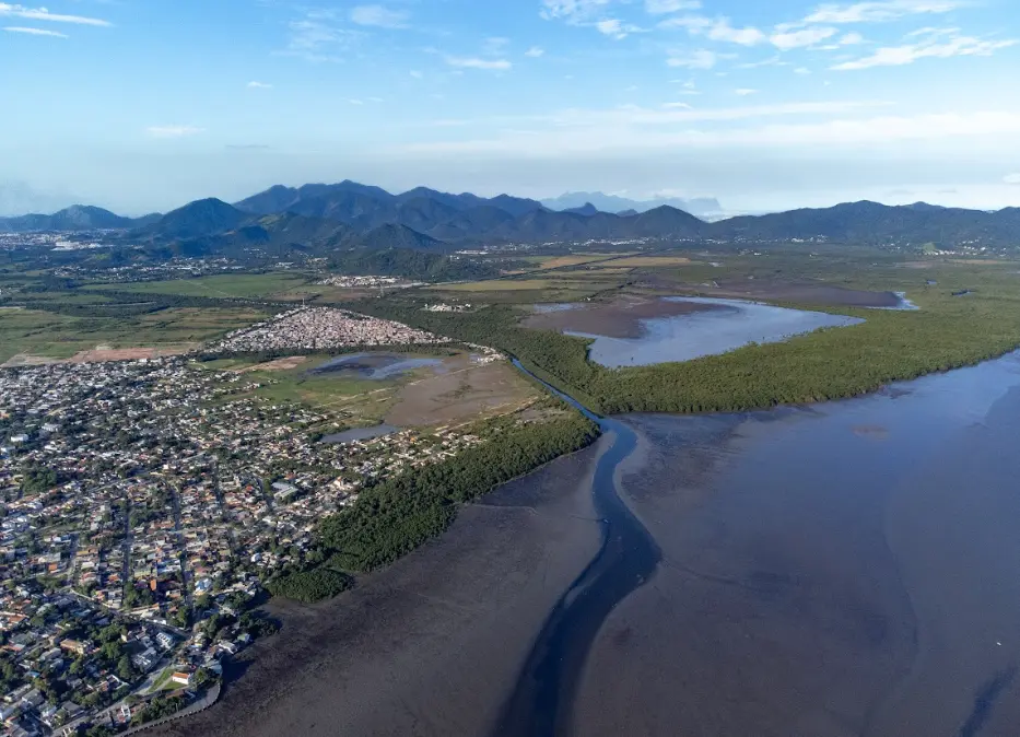 Cidade costeira com rio e manguezais, floresta e montanhas.
