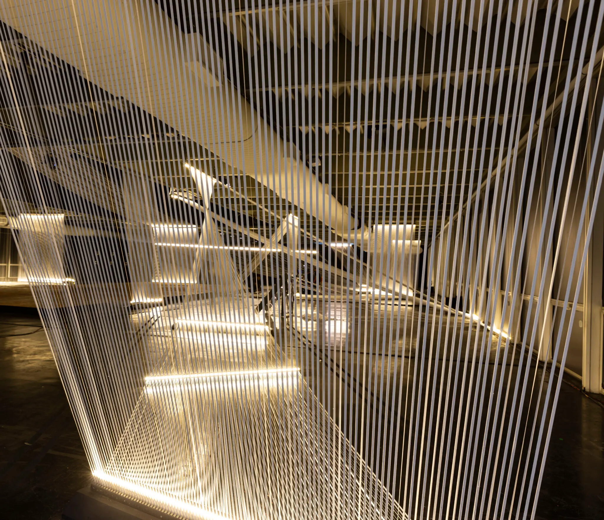 Instalação artística com estrutura geométrica e iluminação branca.