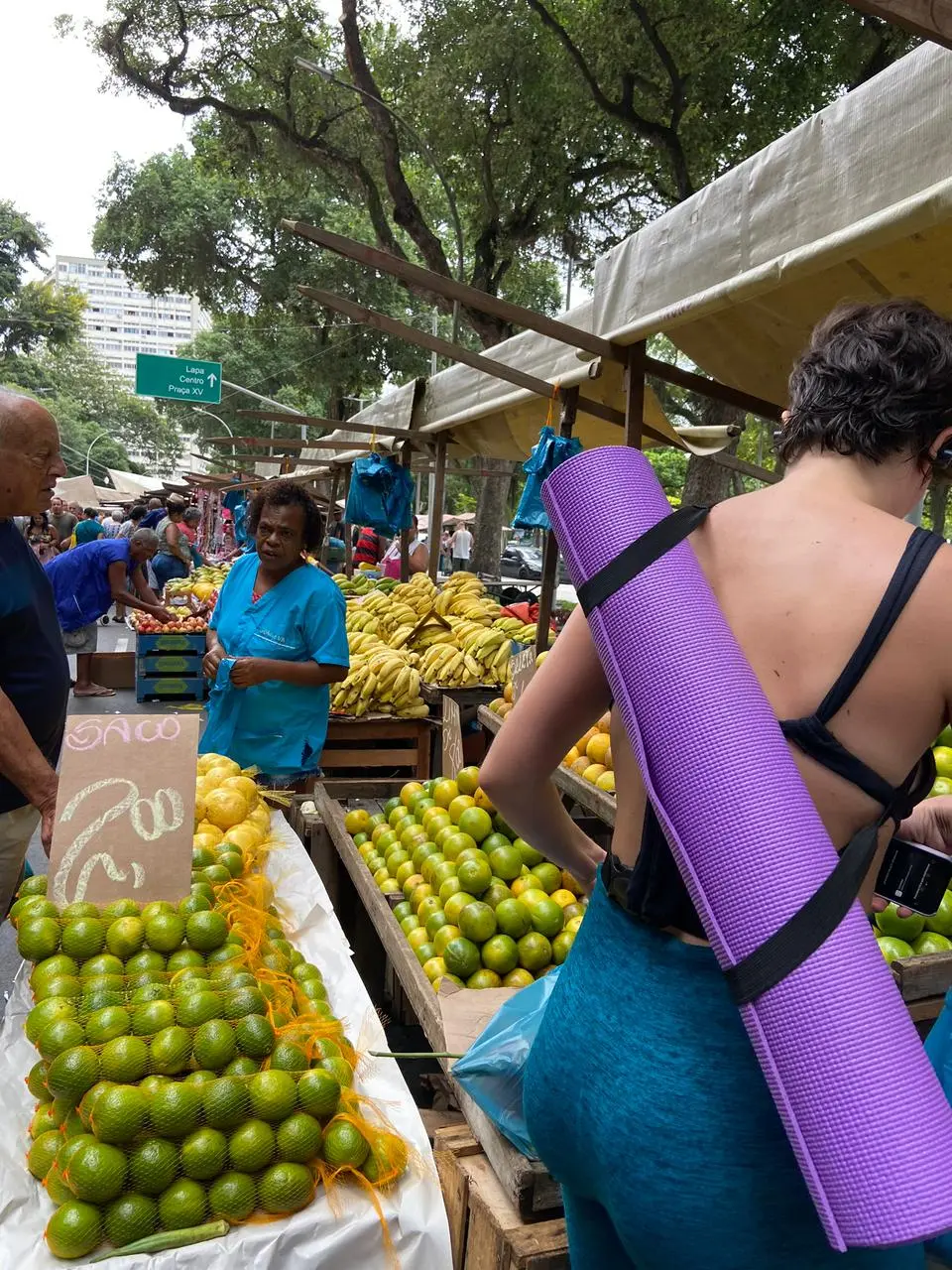 Feira ao ar livre com pessoas e frutas.
