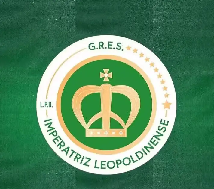 Distintivo verde e branco com coroa dourada e estrelas, assinatura "G.R.E.S." e "L.P.D." sobre fundo verde.