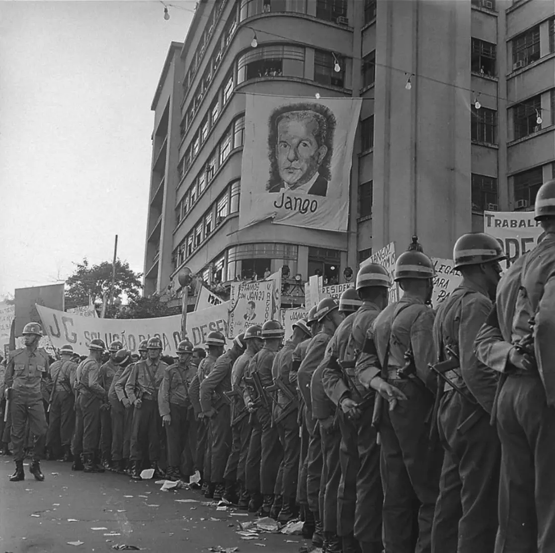 Comício com soldados em uniforme e edifício com banner de Jango.