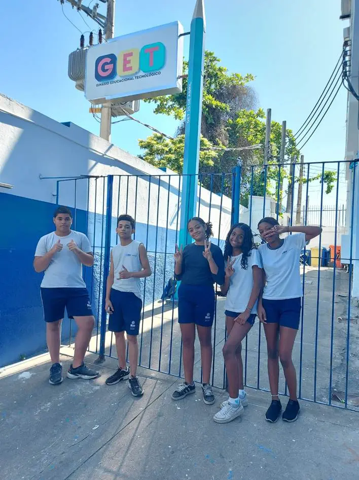 Cinco jovens esportistas em frente a edifício azul com sinal "GET".