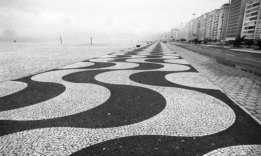 Calçadão de Copacabana com padrões geométricos e mar ao lado.