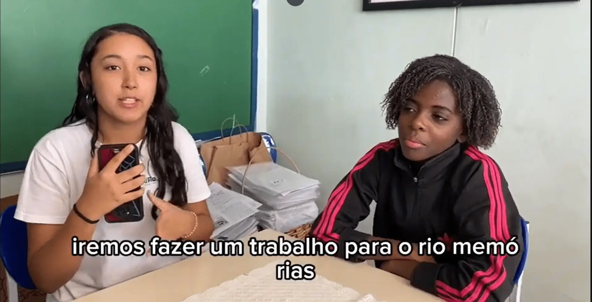 Dois estudantes em sala de aula discutem sobre um projeto relacionado ao rio.