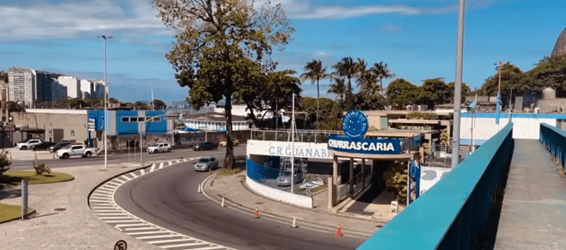 Imagem urbana moderna com churrascaria e palmeiras.