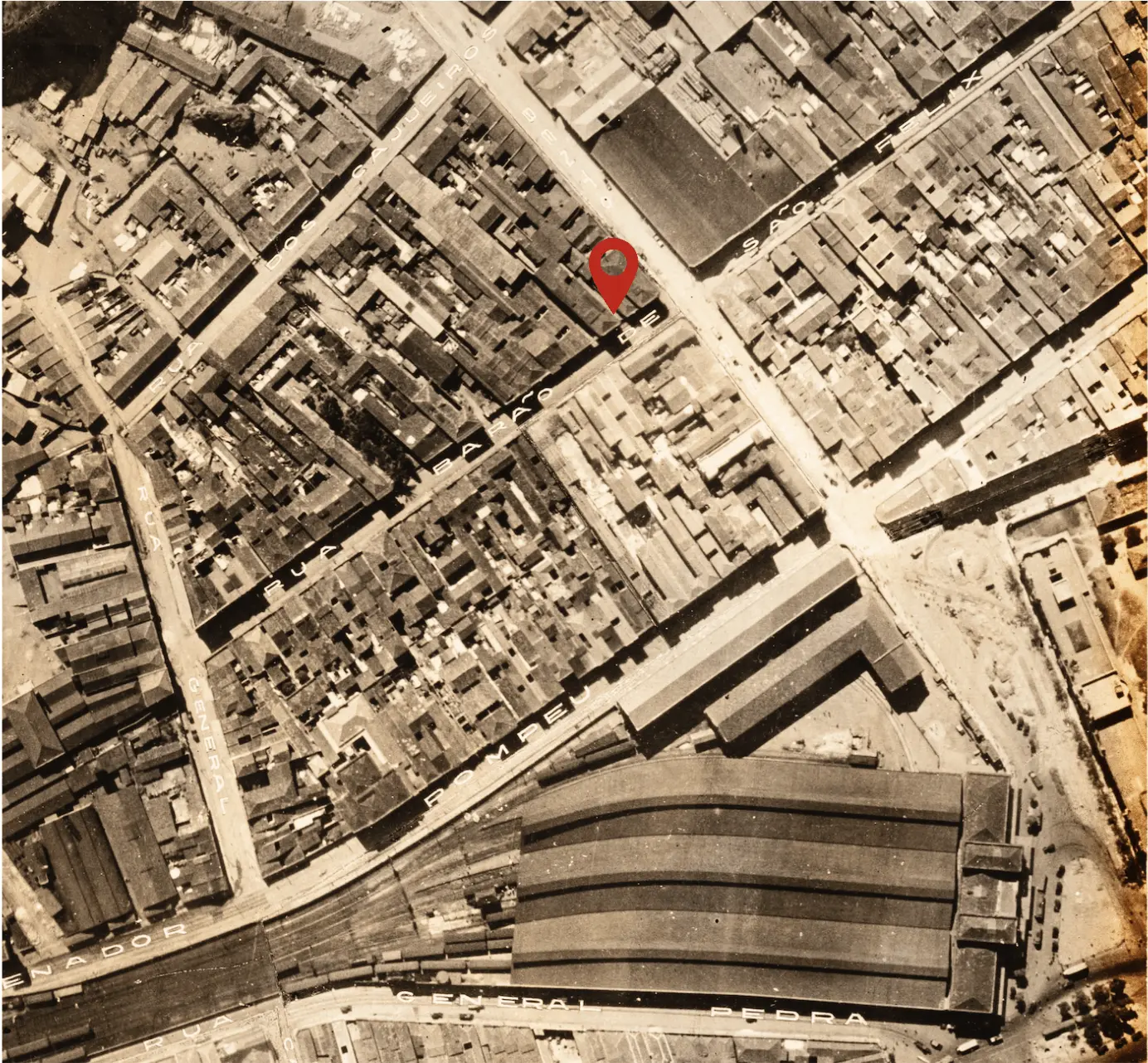 Imagem urbana antiga em tons de sepia, com edifícios e ruas dispostas纵横.