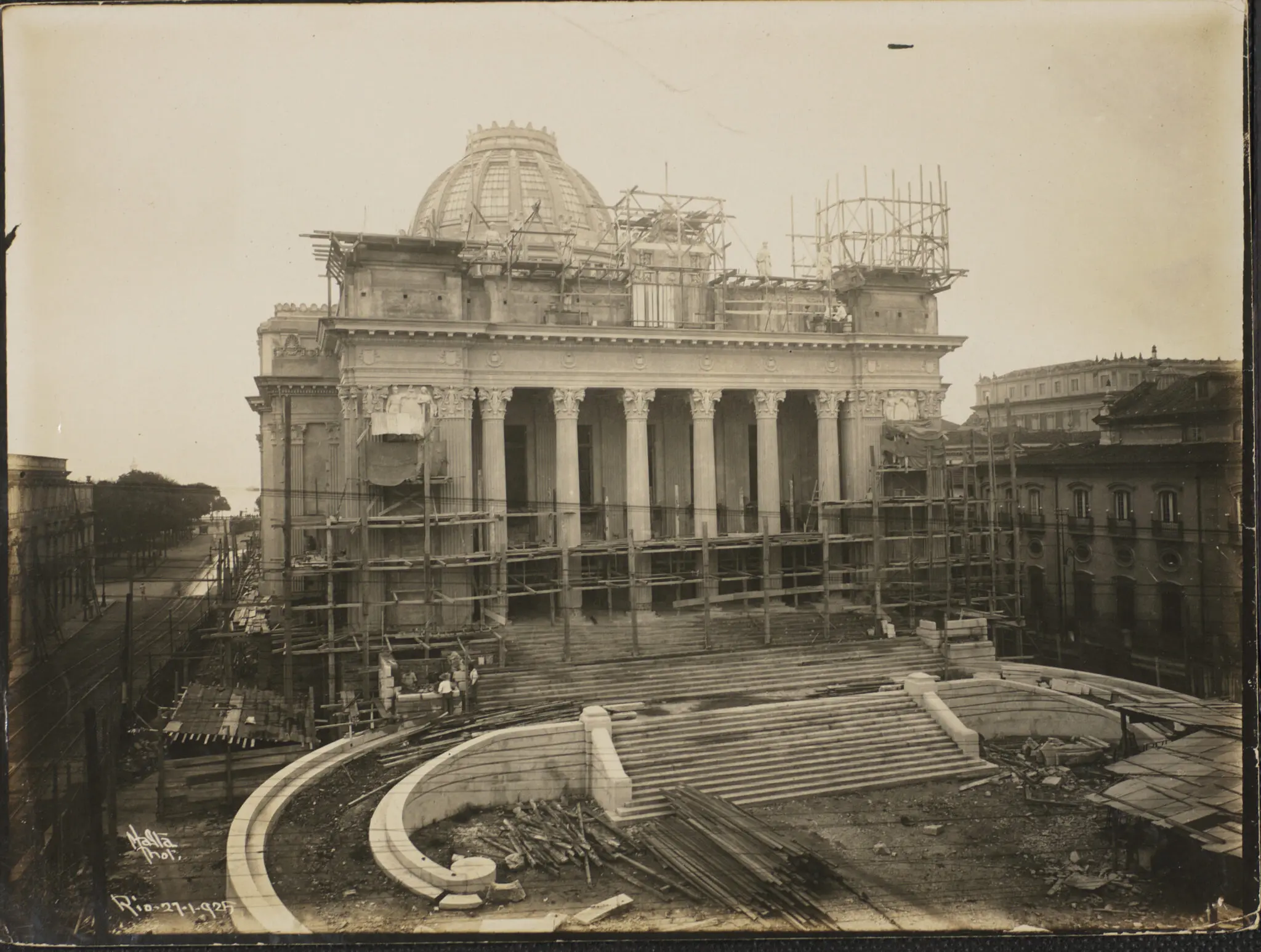 Palácio em construção com fachada clássica e ruas adjacentes.