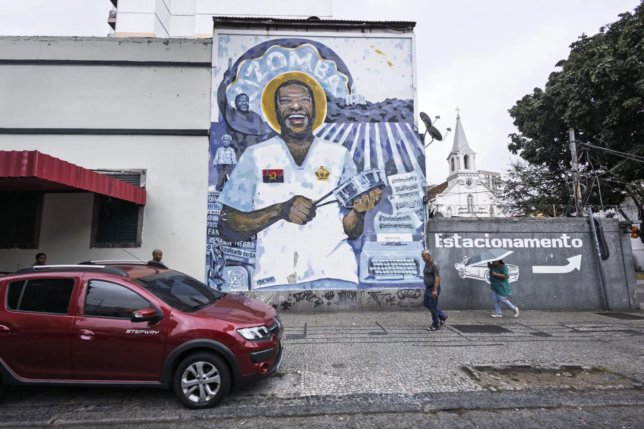 Mural colorido com carro vermelho e figura humana segurando instrumento musical.