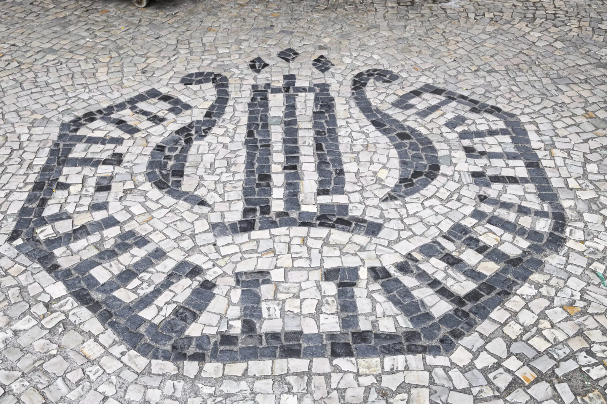 Calçada com padrão artístico e palavra "Bijus" em letras pretas.