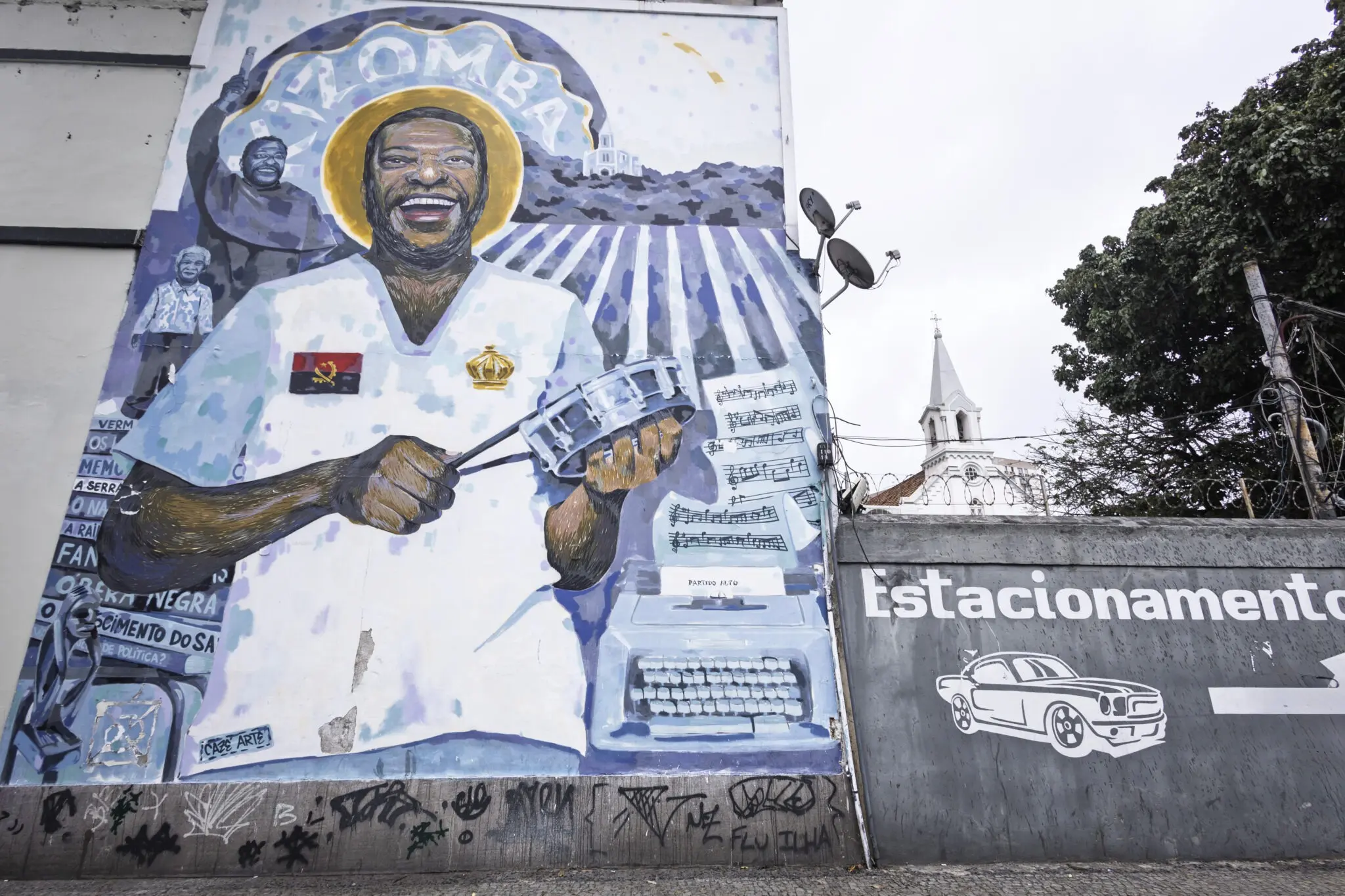 Muralha com pintura de figura sorridente segurando instrumento musical.