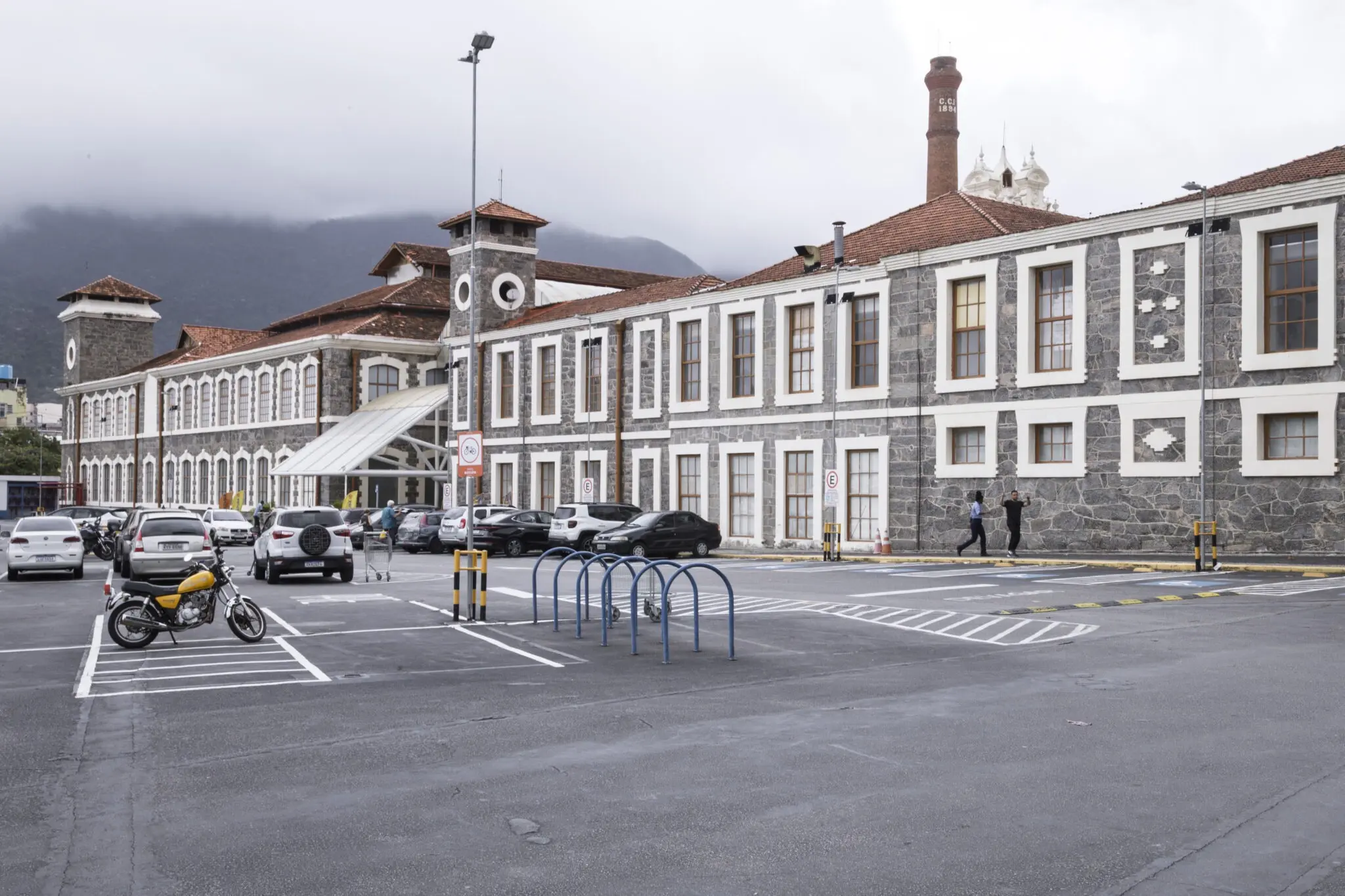 Complexo industrial histórico com estacionamento e bicicletas compartilhadas.