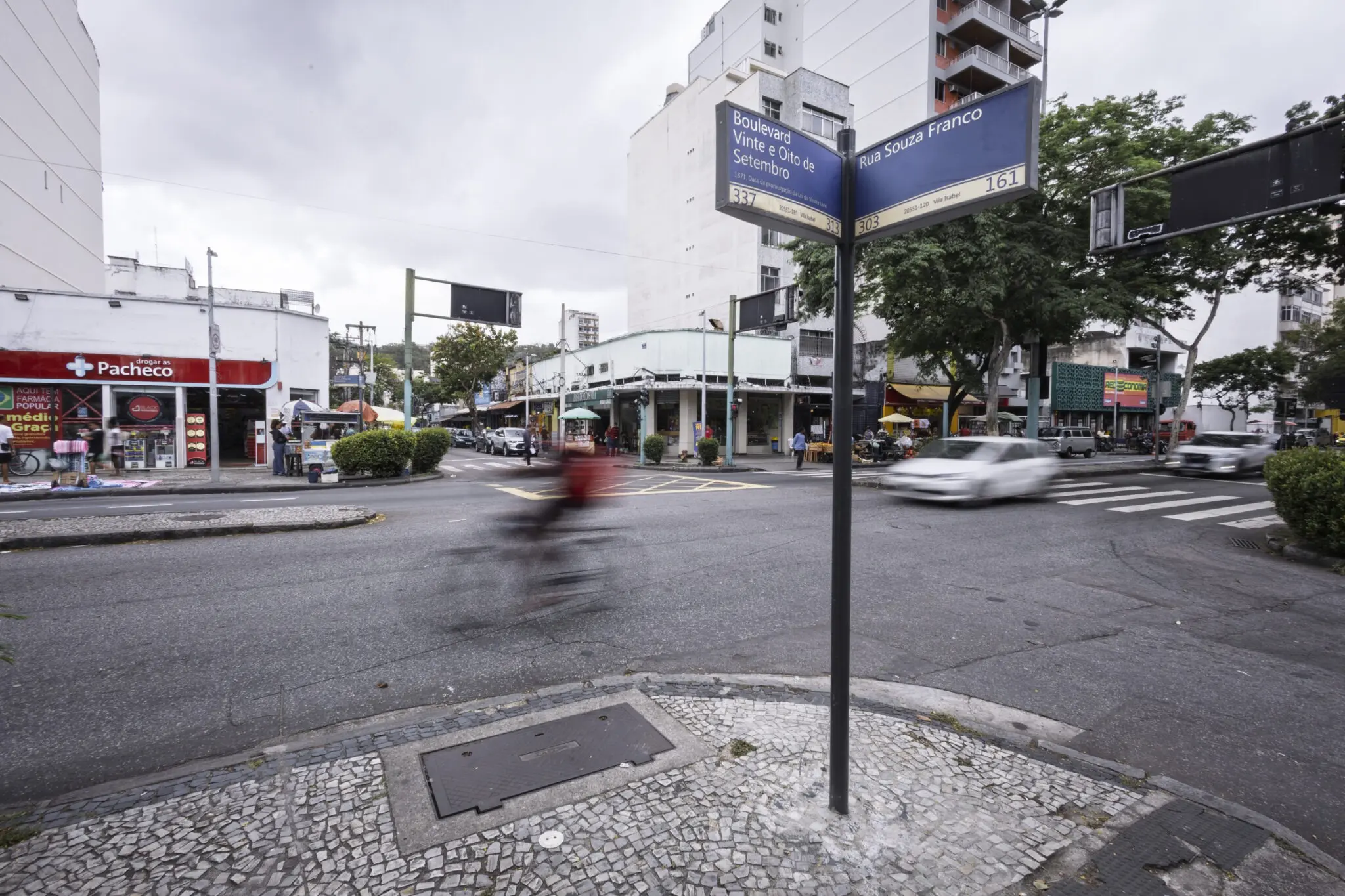 Sinal de direção em rua urbana com edifício comercial e ciclovia.