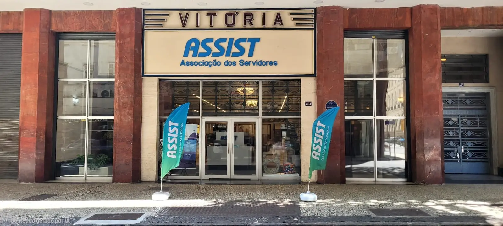 Prédio da Associação dos Servidores Assist com fachada clara e bandeiras azuis.