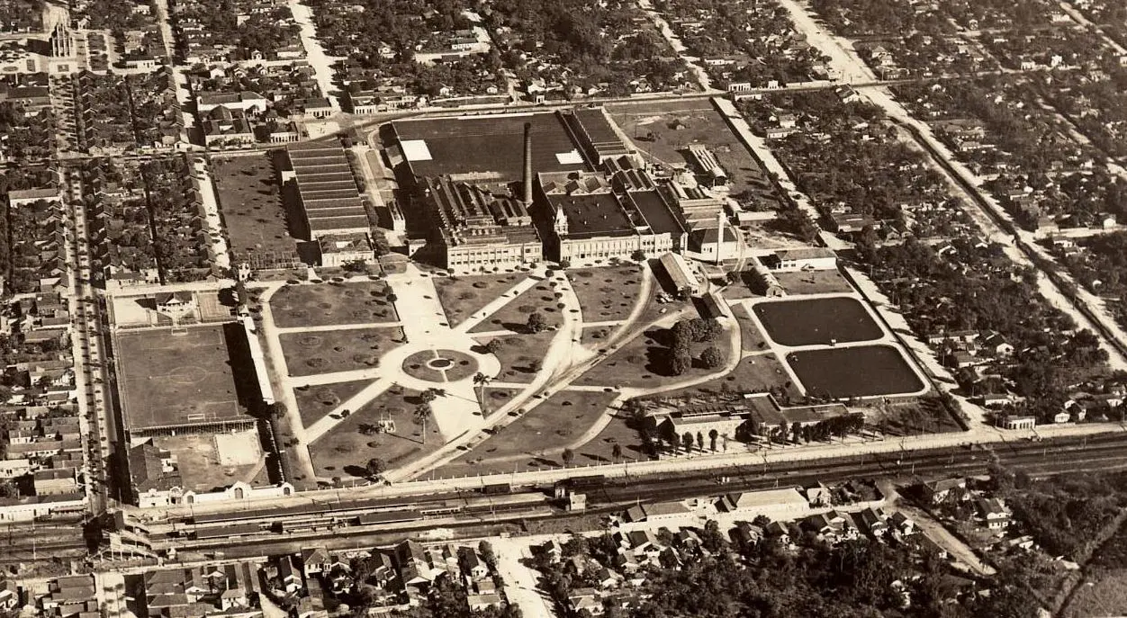 Imagem urbana antiga com edifícios, parque e complexo industrial.