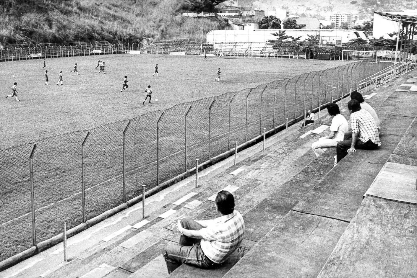 Estádio de futebol com gramado verde e arquibancada de concreto.