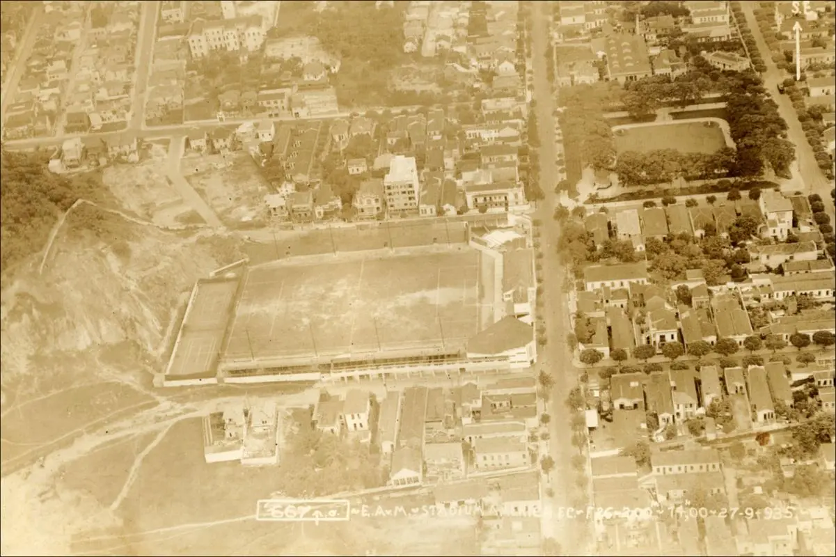 Estádio antigo em área urbana, com pista e arquibancadas.