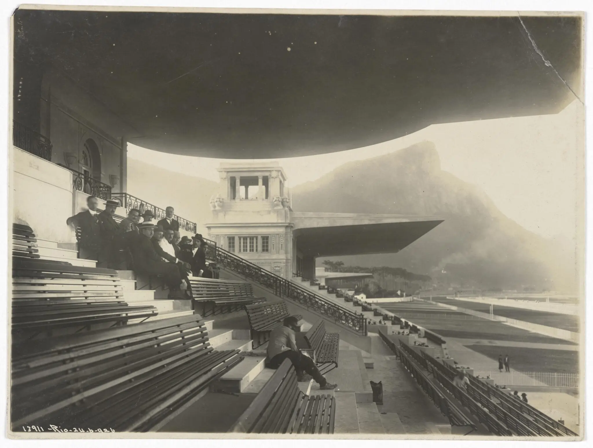 Estádio antigo com bancos vazios e montanha nebulosa ao fundo.