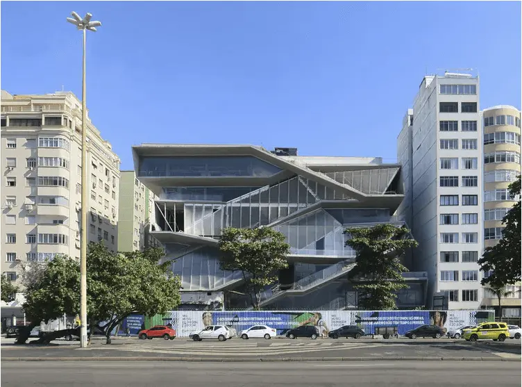 Edifício moderno em ambiente urbano com prédios residenciais e faixa de tráfego.