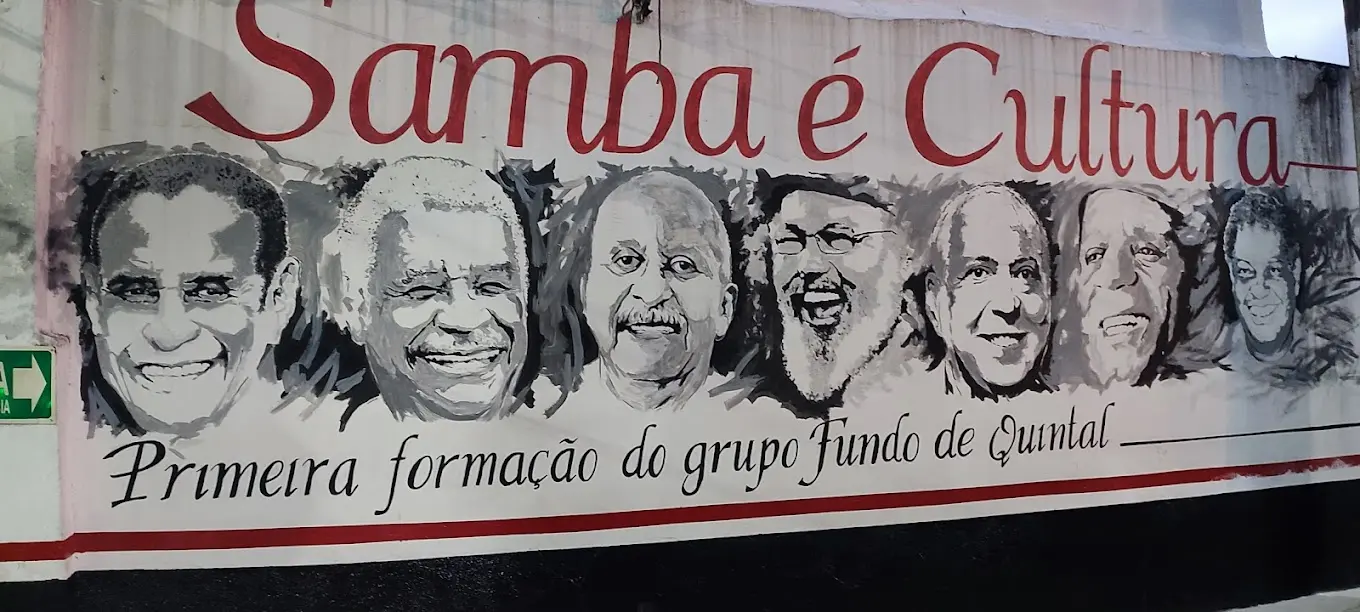 Pintura preto e branco de rostos sorridentes, samba é cultura.