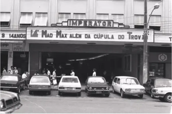 Cinema Imperator com letreiro iluminado, filmes em exibição e loja à direita.