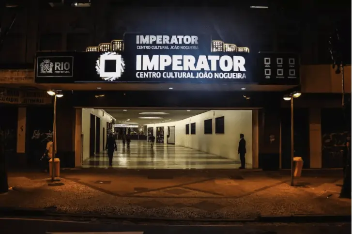 Centro cultural noturno com entrada aberta e iluminação interna.