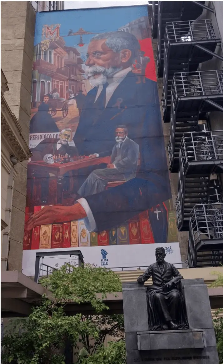 Pintura mural mostrando figura masculina com barba, xadrez e livros.