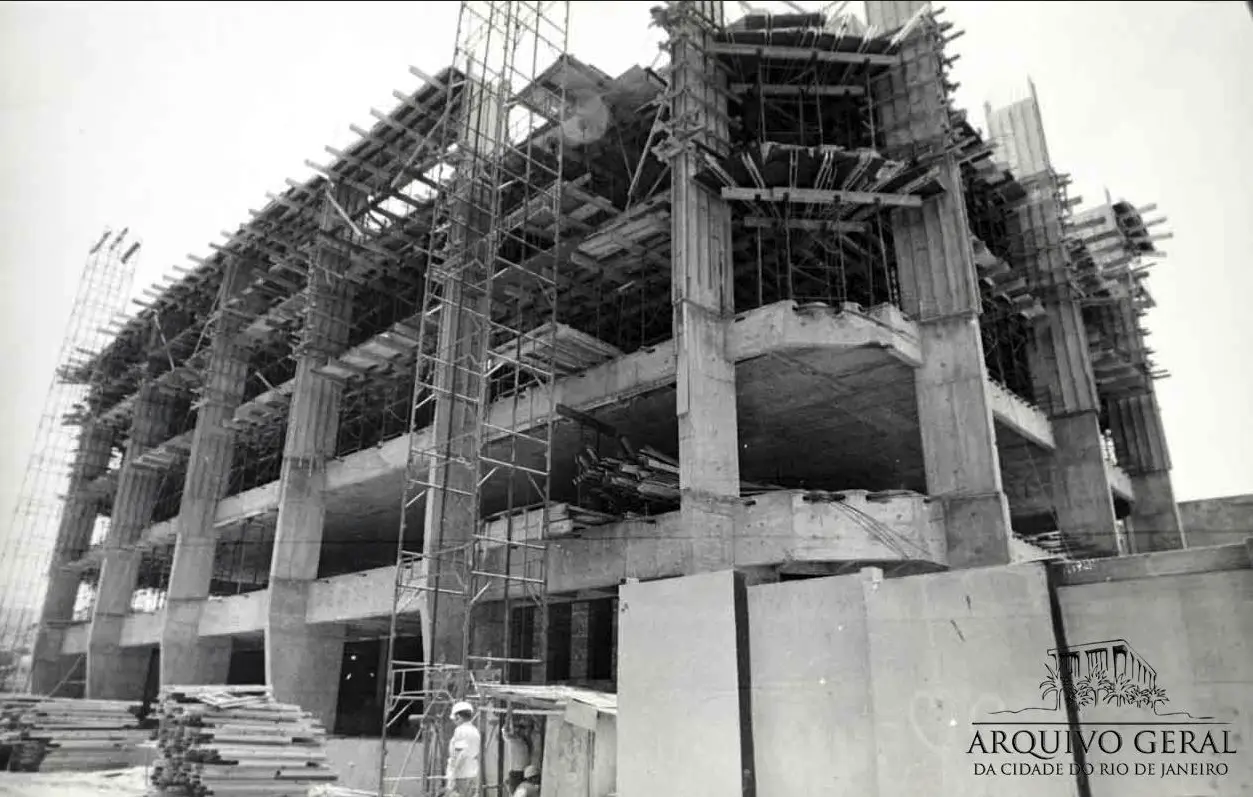 Edifício em construção com andaimes e vigas visíveis.