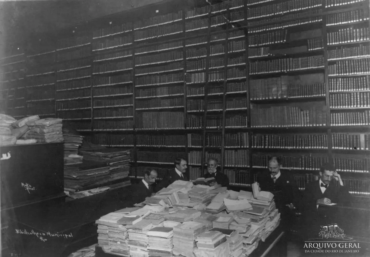 Biblioteca preto e branco com homens concentrados em livros.
