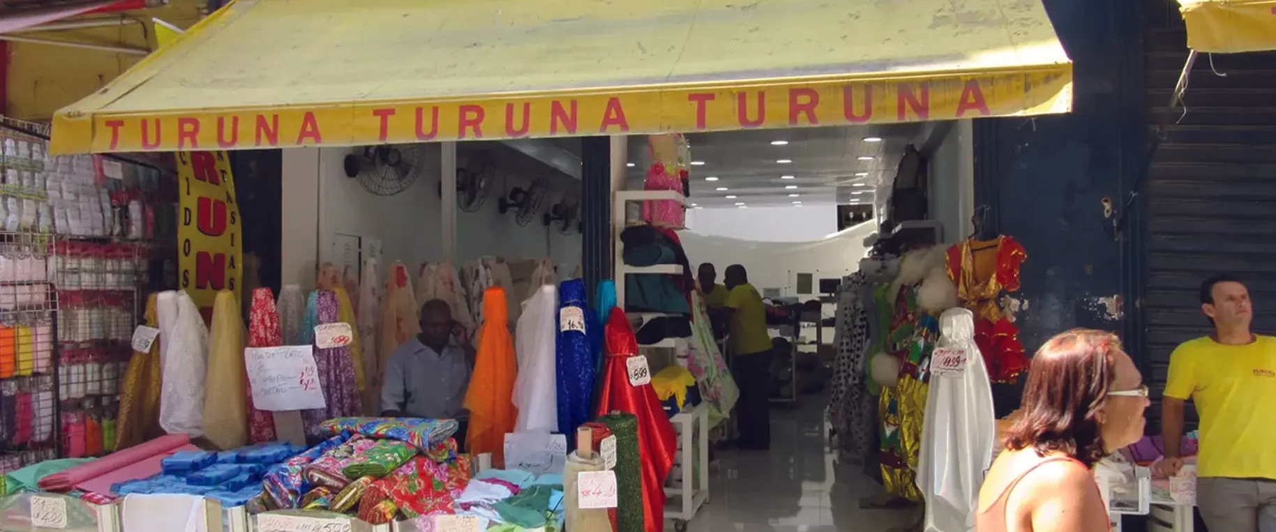 Loja "Turuna" em mercado com tecidos e vestuário.