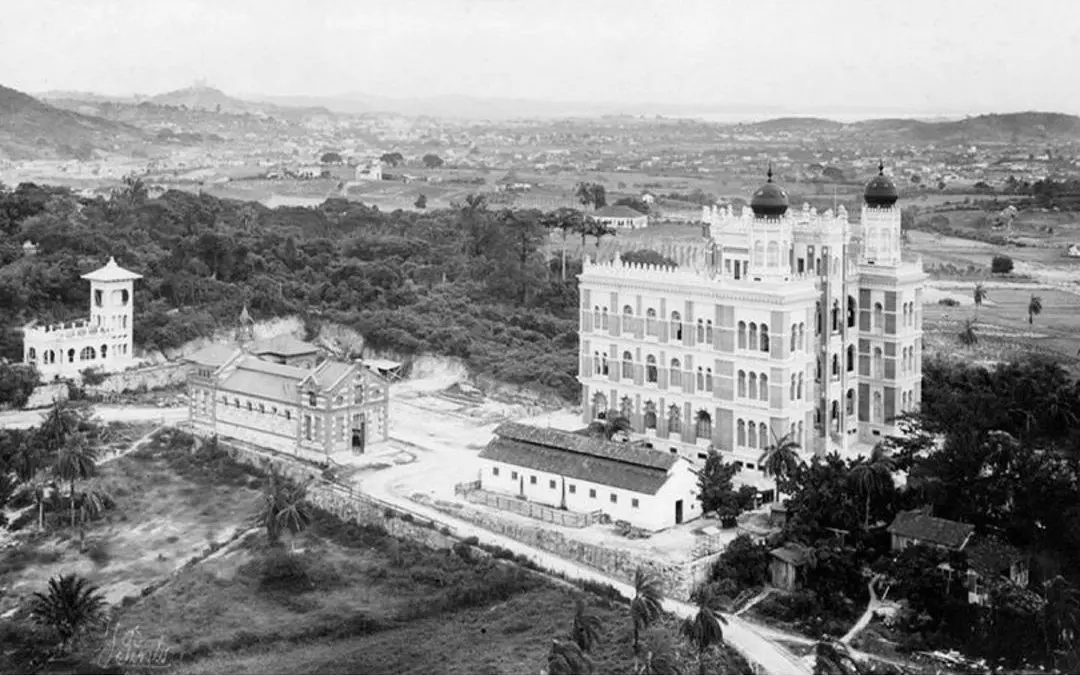 Palácio neomogolista em área verde com edifícios e paisagem montanhosa.