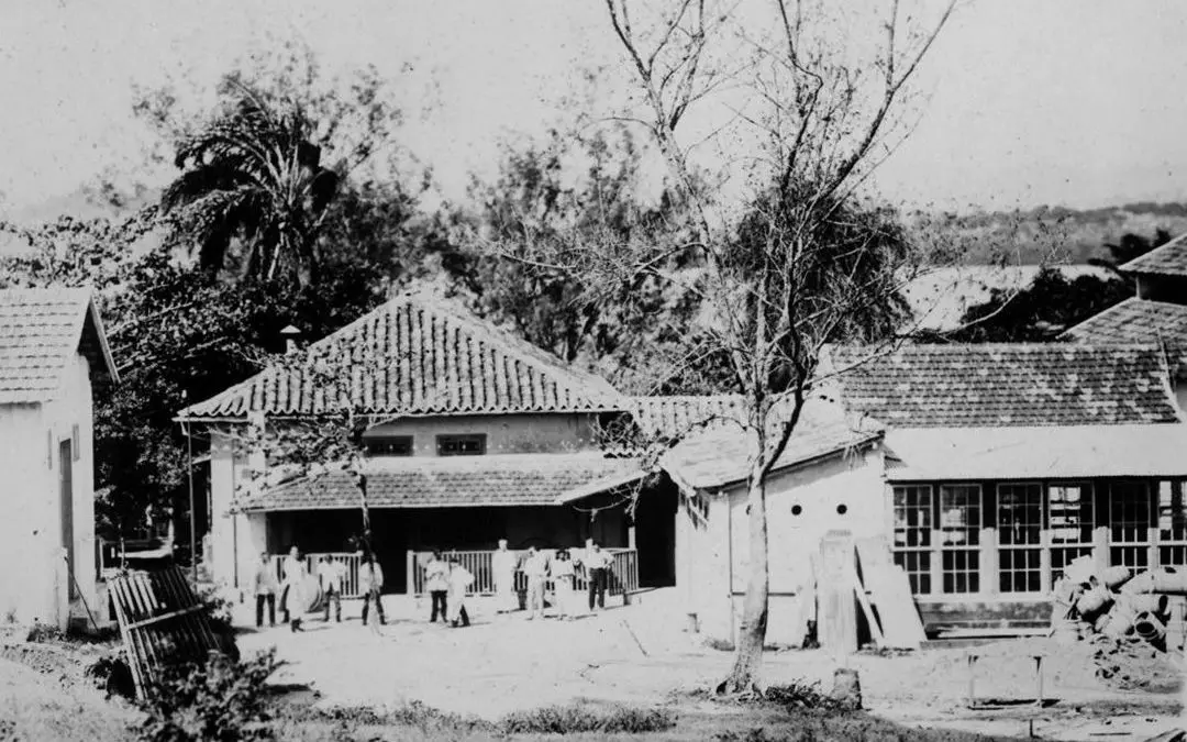 Área rural com construções e pessoas reunidas.