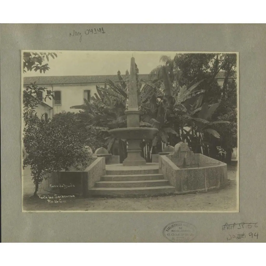 Monumento antigo com árvore e palmeira ao fundo.