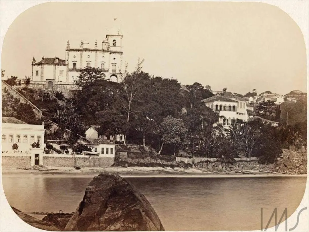Área costeira histórica com edifícios e vegetação.