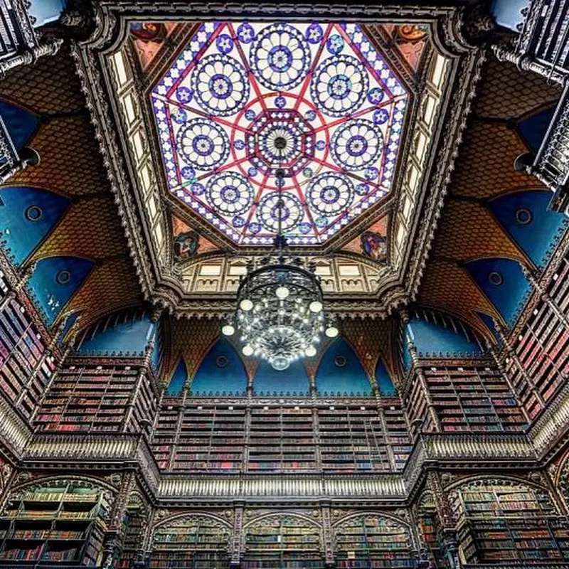 Biblioteca histórica com vitral e lustre.