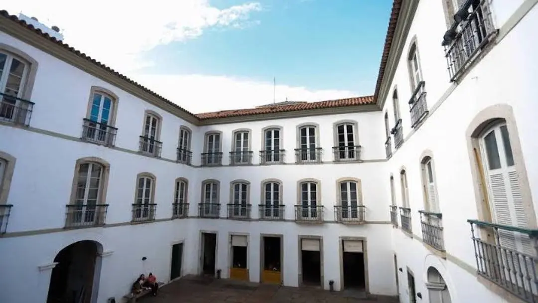 Pátio interno de edifício histórico com pessoa sentada.