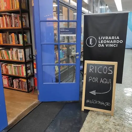 Livraria Leonardo da Vinci com prateleiras de livros, porta azul e logotipo preto.