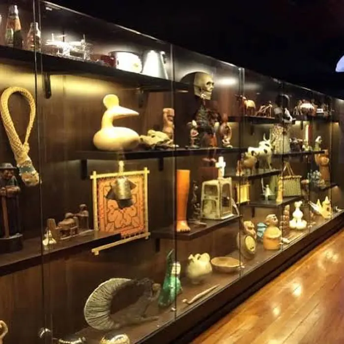 Exposição de objetos tradicionais em prateleiras de vidro.