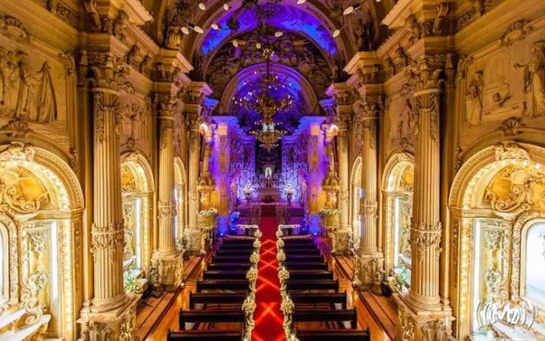 Igreja com colunas douradas, bancos de madeira e altar adornado.