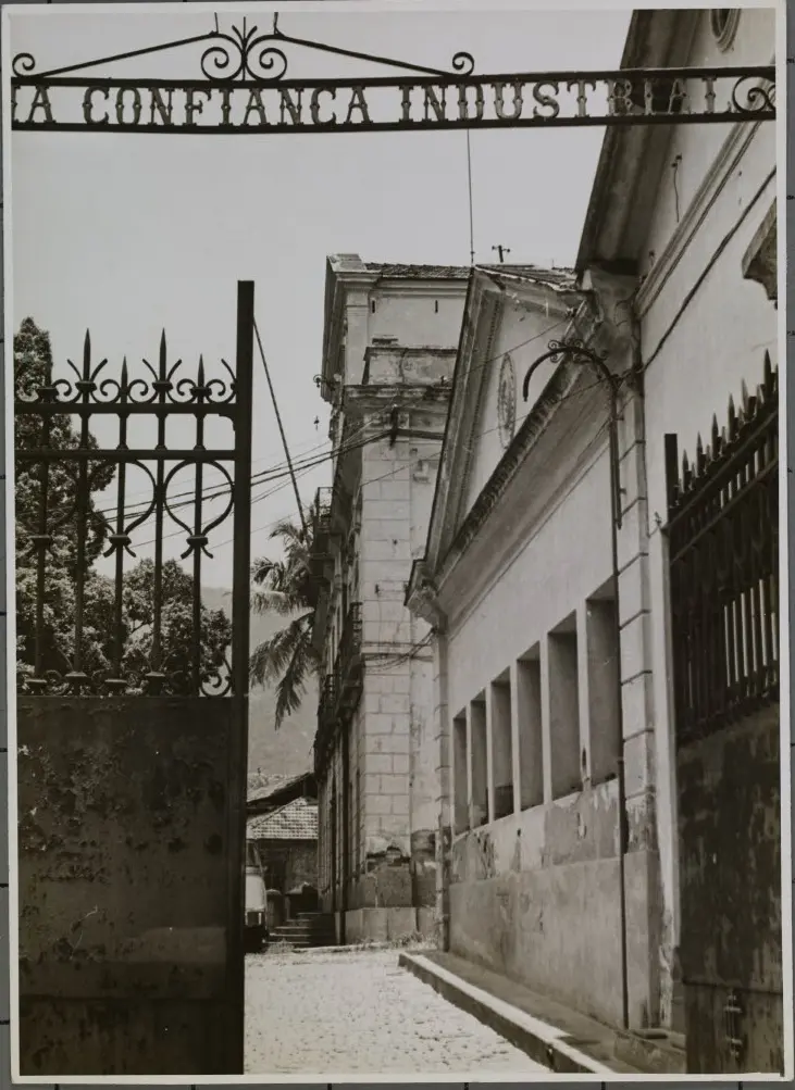 Fábrica industrial com portão metálico e torre antiga.