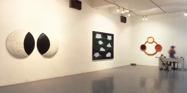 Três obras de arte em uma galeria de arte iluminada.