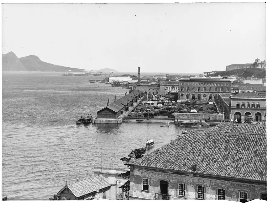 Porto industrial com mar e edifícios históricos.