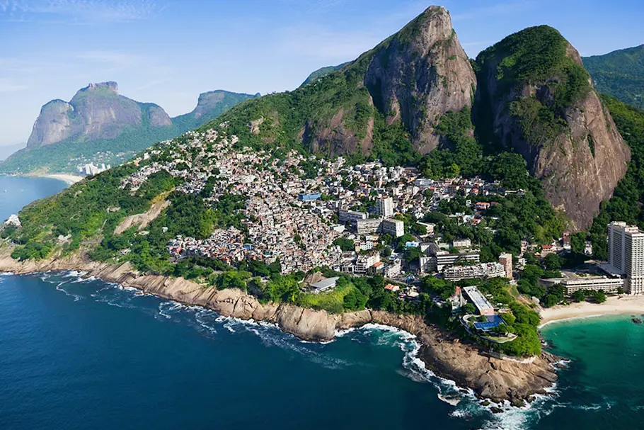 Cidade nas encostas de montanhas com mar azul turquesa e formações rochosas.