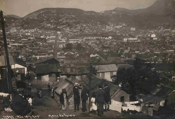 Cidade antiga com vista panorâmica, edifícios variados e montanhas ao fundo.