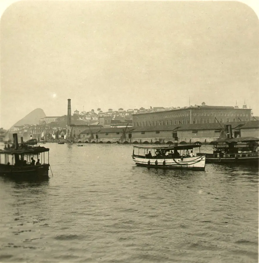 Barcos flutuando em rio histórico com edifícios industriais ao fundo.
